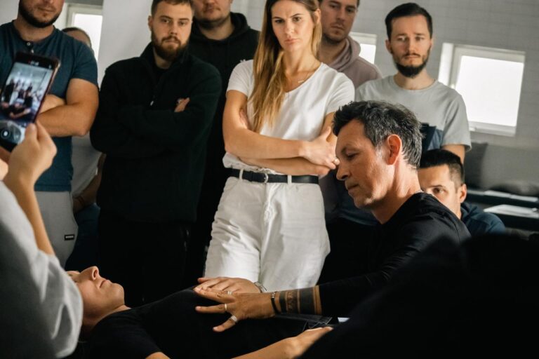 Grupa ludzi przygląda się ćwiczeniom osteopatycznym na modelu